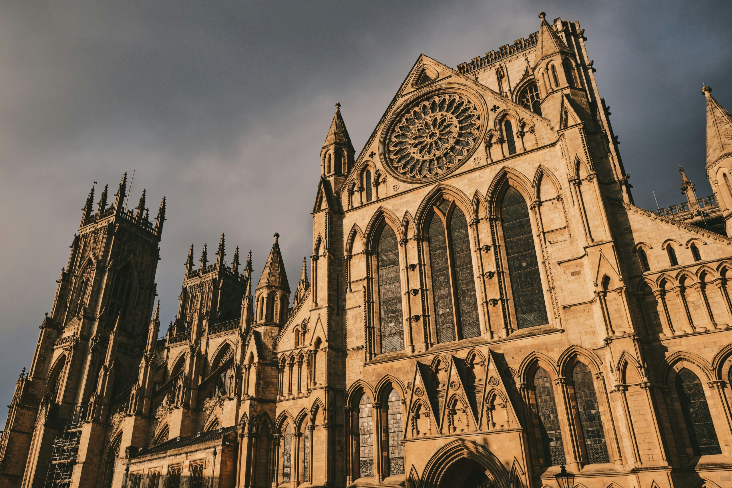 York Minster, a grand Gothic cathedral in York, UK, featuring towering spires, intricate stone carvings, and expansive stained glass windows. The largest Gothic cathedral in England, it dominates the skyline with its twin west towers and central tower, while the Great East Window, the largest expanse of medieval stained glass in the world, adds to its architectural magnificence.